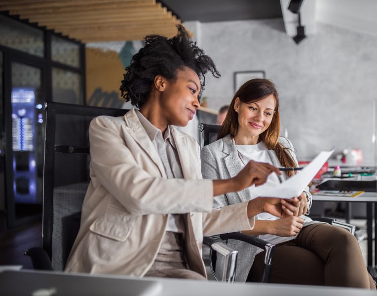 Two businesswomen reviewing document together