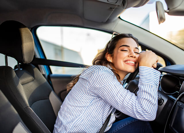 Woman hugging car steering wheel