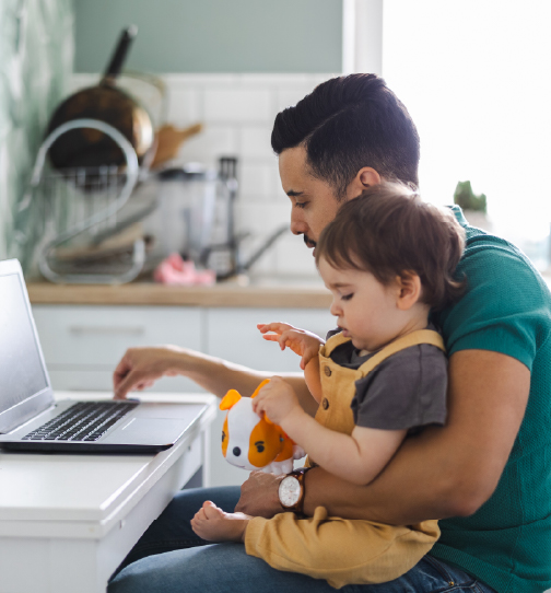 Parent working on laptop with toddler