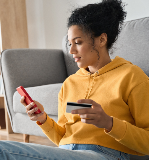 Woman using mobile device in one hand and holding credit card in another