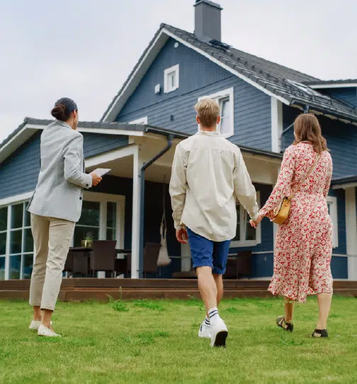 Young couple holding hands while realtor shows them house