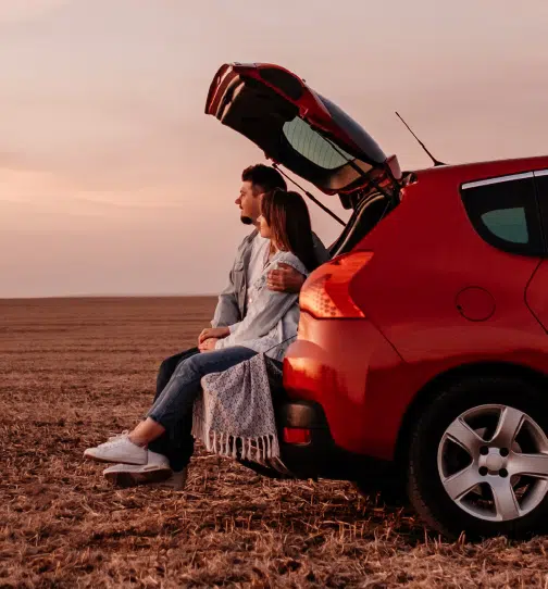Couple sitting in trunk of car looking out in the distance