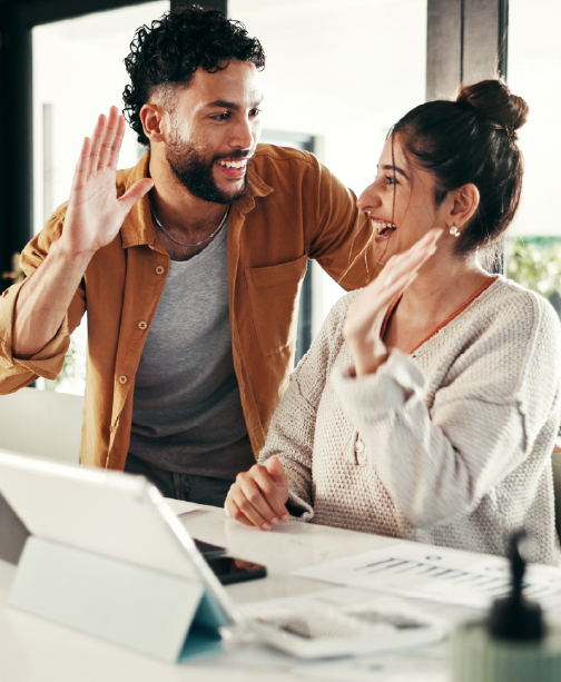 Couple reviewing finances on laptop and high-fiving