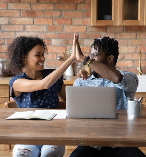 Two people highfiving sitting at table