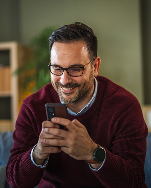 Man smiling while texting on phone
