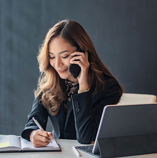 Woman working on laptop while on phone